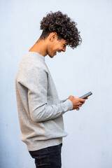 Profile of young North African man looking at mobile phone and laughing