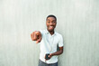 © mimagephotos - laughing young black man with mobile phone and earbuds pointing finger