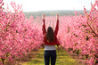 © PheelingsMedia - Excited woman raising arms in a flowered field in spring