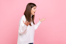 Side View Portrait Of Young Girl Holding Hands In Mad Furious Gesture, Screaming With Rage And Anger, Wearing White Casual Style Sweater. Indoor Studio Shot Isolated On Pink Background.