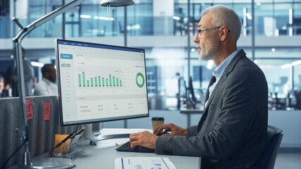 Corporate Office: Senior IT Specialist Using Desktop Computer with Big Data Statistics, Graphs. Smiling Creative Software Engineer Work on eCommerce Project Marketing, Development.