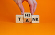 Think tank symbol. Businessman turns a wooden cube and changes the word tank to think. Beautiful orange table, orange background, copy space. Business and think tank concept.
