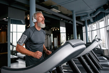 Aged man on treadmill, running over the top