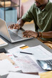 © pressmaster - Hands of young African male economist working in front of laptop while sitting by table with financial documents