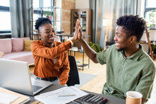 Happy Young Couple Or Colleagues Of African Ethnicity Giving Each Other High-five While Working Together By Table