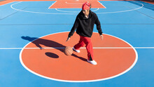 Asian Man Dribbling Basketball Ball On Playground