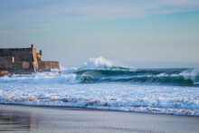 Large Waves Crash Into A Fortress Near A Beach. Carcavelos Beach In Portugal