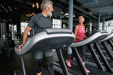 Wall Mural - Handsome aged man flirting with lovely middle-aged woman in gym