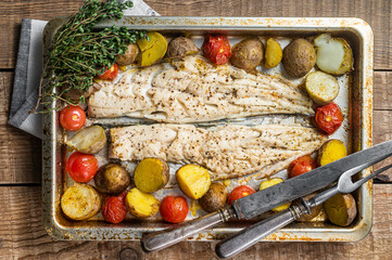 Wall Mural - Hake fish fillet, roasted fish meat with tomato and potato. Wooden background. Top view