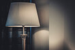 A lit table lamp with a white shade on the nightstand
