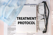 the treatment protocol is written on a notebook that is on the sick-list. Medical mask and eyeglasses