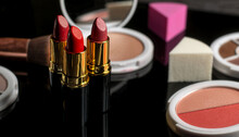 Various Makeup Products On A Black Reflective Table
