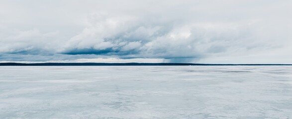 Frozen forest lake on a cloudy day. Dramatic sky after a blizzard. Onega, Karelia, Russia.Atmospheric winter landscape. Panoramic view. Nature, climate change, christmas vacations, eco tourism