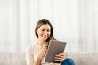 © Dusan Petkovic - A happy woman on the sofa having video call on the tablet at her home.