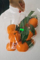 Sticker - hand holding up bag of mandarin oranges from the fruit stand with green price sticker