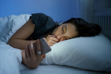 Young Anxious Asian Woman Lying In Bed Staring At Smartphone Screen At Night, Reading About Depression Symptoms In Internet, Phone Addicted Female Can Not Stop Scrolling Social Media Before Bedtime
