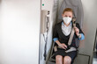 Stewardess in medical mask fastening seatbelt in aircraft