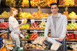 Portrait of cheerful man with purchases in cart after shopping in greengrocery store