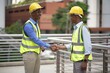 © Stock Media Labs - Two construction workers wearing hard hats and reflective vests shaking hands outdoors, highlighting teamwork and successful collaboration in a construction project.
