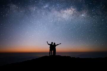 Wall Mural - Silhouette of couple of lovers watched the star and milky way alone on top of the mountain. He enjoyed traveling and was successful when he reached the summit
