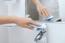 Cleaning The Sink Faucet With A Microfiber Cloth. Sanitize Surfaces Prevention In Hospital And Public Spaces Against Corona Virus. Woman Hand Using Wet Wipe. Cleaning The Bathroom.