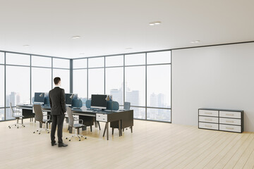 Wall Mural - Businessman standing in modern concrete coworking office room interior with panoramic window wooden parquet flooring, with city view, equipment, daylight and furniture.