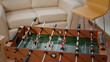 Close up of foosball game and bottles of beer with snacks on table for party celebration with colleagues after work in office. Toy for football play with players and ball for goal for fun