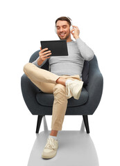 Canvas Print - people, technology and music concept - happy smiling man with headphones and tablet pc computer sitting in chair over white background