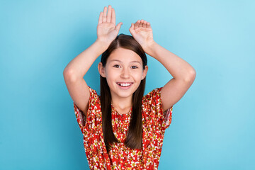 Sticker - Photo of young cheerful pretty girl good mood show arms rabbit ears isolated over blue color background