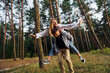© standret - Woman is riding her man. Happy couple is outdoors in the forest at daytime