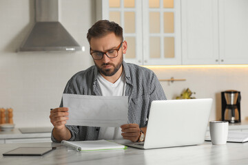 Wall Mural - Young man working with document and laptop at home