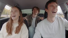 A Small Group Of People Are Laughing And Riding In A Car. People Are Driving In A Car