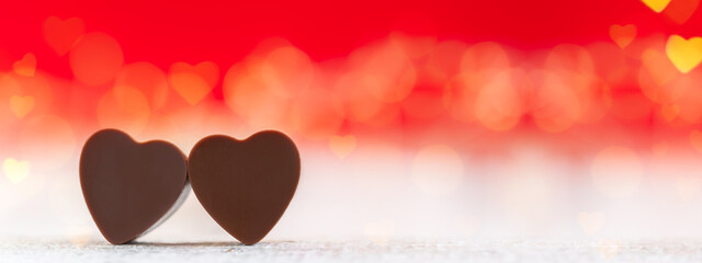 Wall Mural - Heart shaped chocolates on red background with boke. Happy Valentine's Day greeting card. Banner