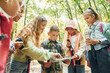 © standret - Using map. Kids in green forest at summer daytime together