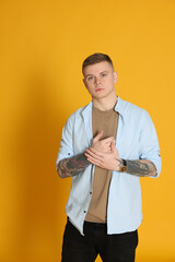 Wall Mural - Young man with tattoos on yellow background