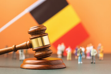 Wall Mural - Wooden judge gavel, flag and plastic toys on a colored background, the concept of litigation in the Belgian society