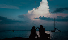 Couple Man And Women In Love Staying On Seaside With Sunset Scenery People  Romantic Reltionship And Friendship Concept.