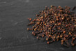 Leinwandbild Motiv Pile of aromatic dry cloves on black table, closeup. Space for text