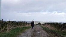 Solitary Woman Walking Through Isolated Countryside Road In Yorkshire England