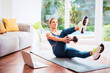© gzorgz - Shot of a middle aged woman using laptop while exercising at home