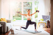 © gzorgz - Shot of a middle aged woman using laptop while exercising at home