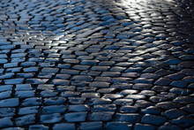 Cobblestone Street In Iserlohn Sauerland Germany. Wet Shiny Historic Basalt Ashlars Or Blocks Reflecting Blue Sky And Sunshine After Rain. Old Pavement Background With Typical Surface And Structure.