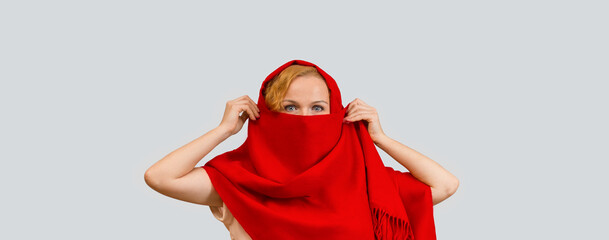 woman covering her face with red scarf and looking at the camera, isolated on white background