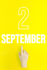 September 2nd. Day 2 of month, Calendar date.Hand finger pointing at a calendar date on yellow background.Autumn month, day of the year concept.