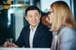 © Liubomir - Two employees are having fun. Asian man and blonde woman taking a break, colleagues working together in a modern office