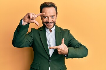 Middle age man wearing business suit smiling making frame with hands and fingers with happy face. creativity and photography concept.