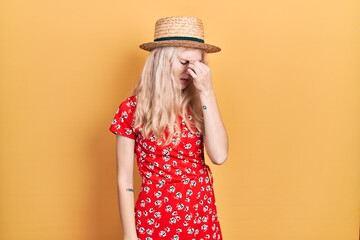 Canvas Print - Beautiful caucasian woman with blond hair wearing summer hat tired rubbing nose and eyes feeling fatigue and headache. stress and frustration concept.