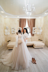 Wall Mural - bride in white coat by wedding dress in room of her house. sofa with balloons.