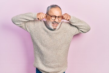 Poster - Handsome senior man with beard wearing casual sweater and glasses smiling pulling ears with fingers, funny gesture. audition problem