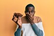 © Krakenimages.com - Young african american man holding bowl with raisins covering mouth with hand, shocked and afraid for mistake. surprised expression